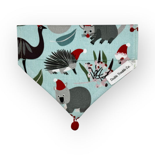 A light blue bandana with a Christmas-themed pattern featuring various cartoon animals, including a koala and a kangaroo, wearing Santa hats and Santa Claus himself.
