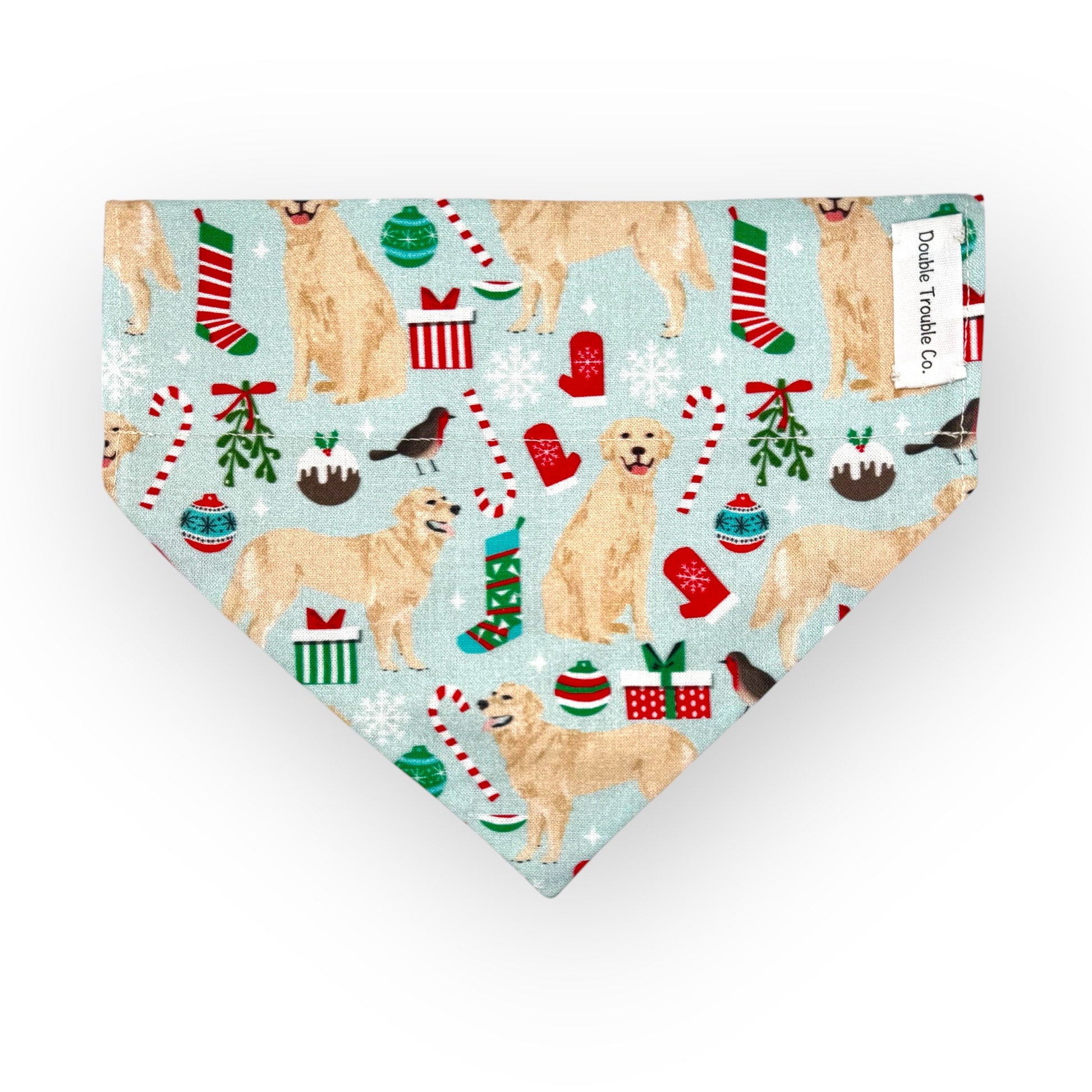 A bandana with a Christmas themed pattern featuring illustrations of golden retrievers, gifts, stockings, and candy canes on a snowy background.